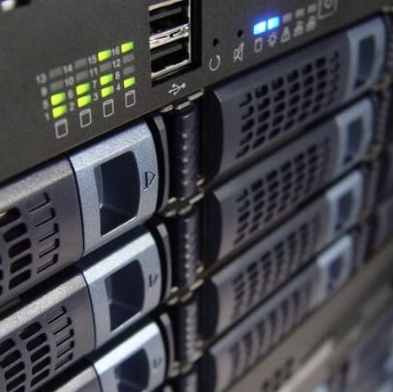 Close-up of the front panel of a server rack showing multiple hard drive bays, indicator lights, USB ports, and ventilation grilles.