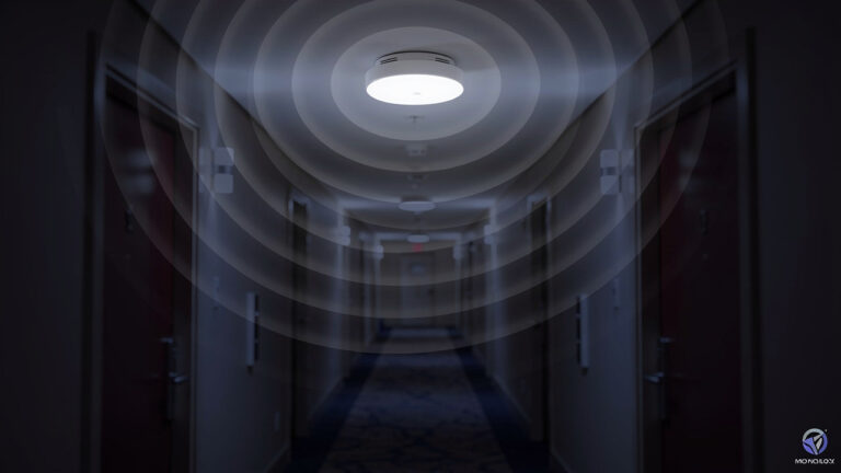 A smoke detector on a hallway ceiling emits visible circular waves, suggesting the detection or transmission of signals.