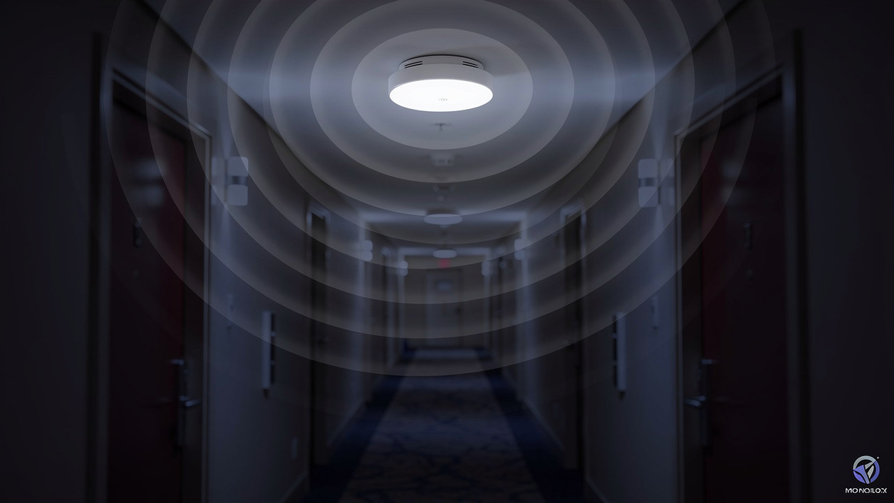 A smoke detector on a hallway ceiling emits visible circular waves, suggesting the detection or transmission of signals.