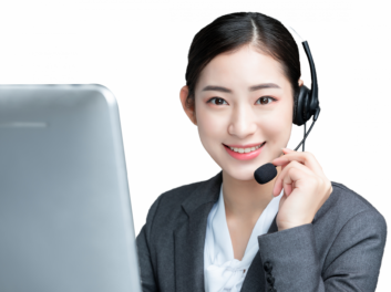 A woman wearing a headset and business attire sits in front of a computer, smiling at the camera. A woman wearing a headset and business attire sits in front of a computer, smiling at the camera.